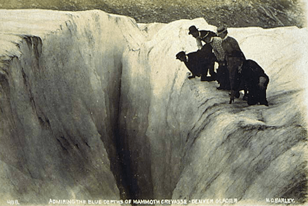 Excursion party at Denver Glacier peering into a crevasse, Alaska, ca. 1900.